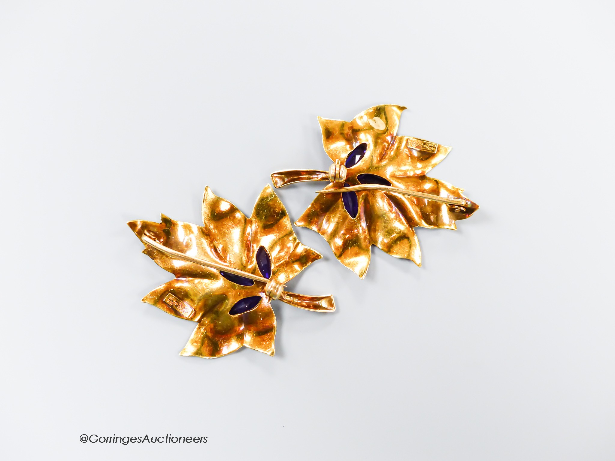 A pair of 750 yellow metal and three stone amethyst set leaf brooches, 38mm, gross 11.2 grams.